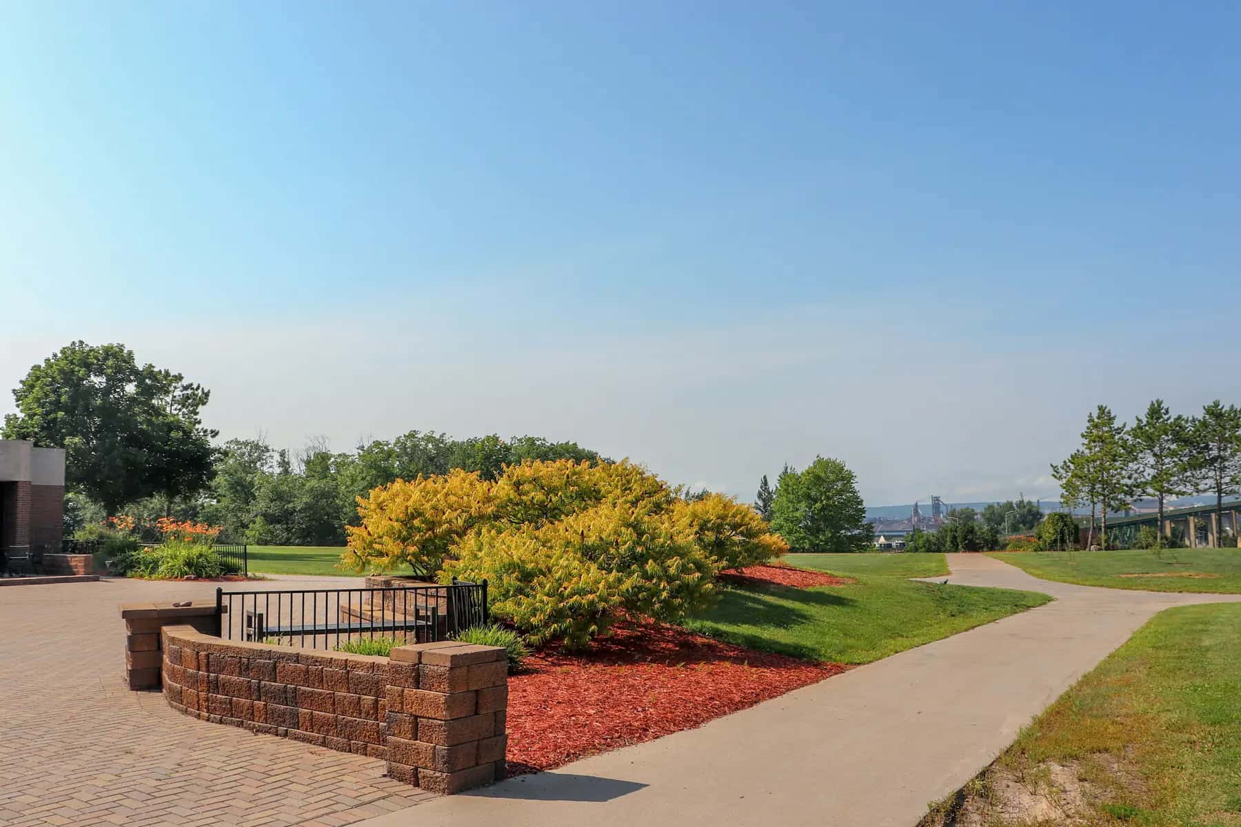 Manicured grounds with trimmed shrubs, fresh red mulch, a brick planter wall and a clean walkway
