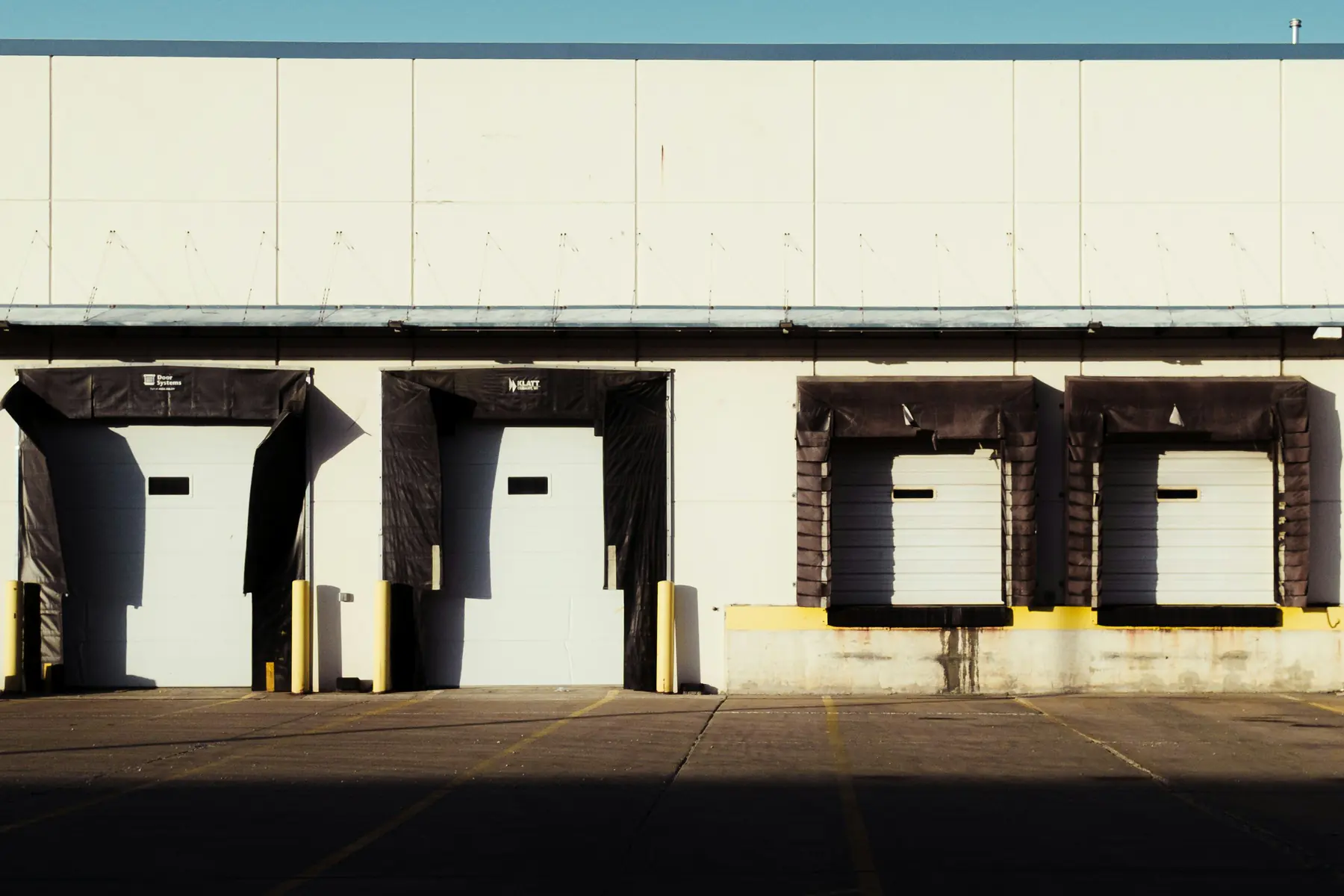 Row of truck loading docks on the exterior of a white warehouse