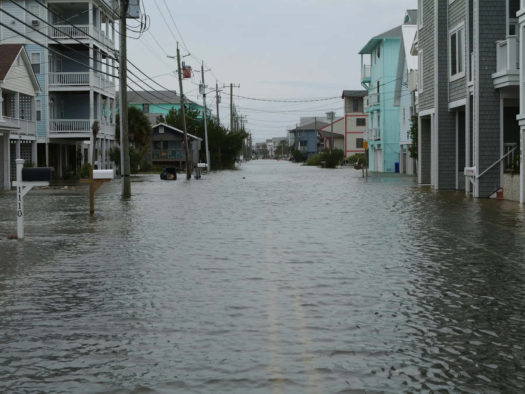 Flooded coastal street lined with raised homes and utility poles