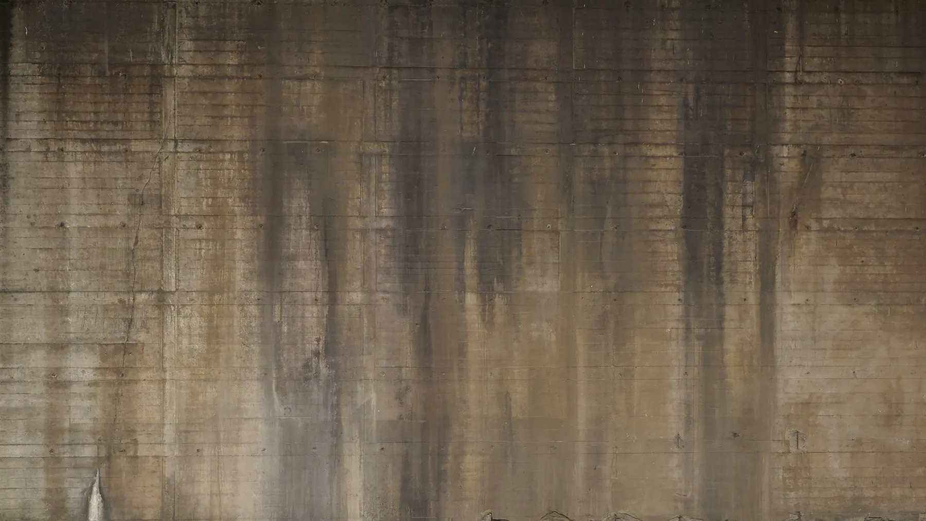 Concrete wall with dark water streaks, grime and staining
